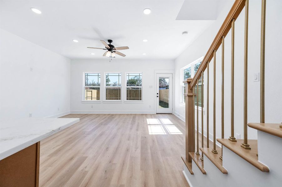 Bright living area with abundant natural light, wood-style flooring, and backyard access.