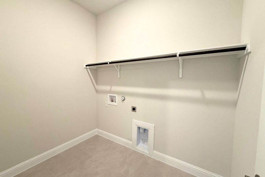 A dedicated laundry space provides practical utility with an elevated shelf and essential hookups. A dedicated laundry space provides practical utility with an elevated shelf and essential hookups.