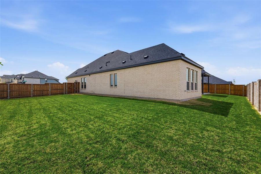 Rear view of property featuring a fenced backyard and brick siding Rear view of property featuring a fenced backyard and brick siding