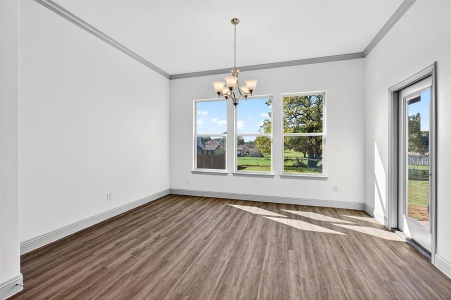 Unfurnished dining area with wood finished floors, ornamental molding, and a chandelier
