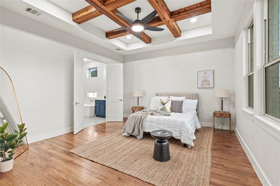Bedroom with coffered ceiling, wood finished floors, beamed ceiling, connected bathroom, and multiple windows Bedroom with coffered ceiling, wood finished floors, beamed ceiling, connected bathroom, and multiple windows