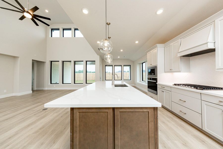 Three stunning clear glass orb pendant lights create an instant focal point above the kitchen island, offering both essential task lighting and a touch of modern sophistication.