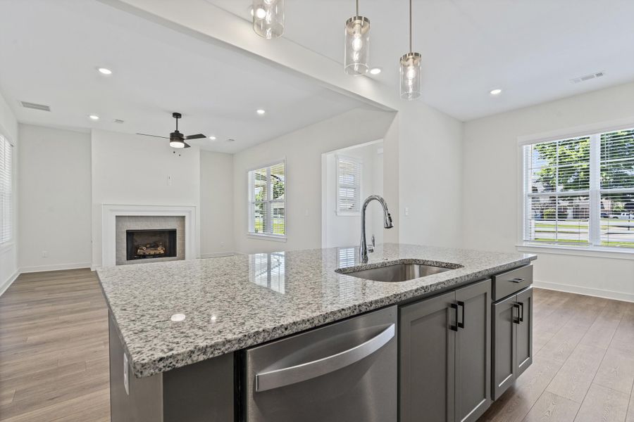 Kitchen island featuring a stainless steel undermount sink, gooseneck faucet, and integrated dishwasher
