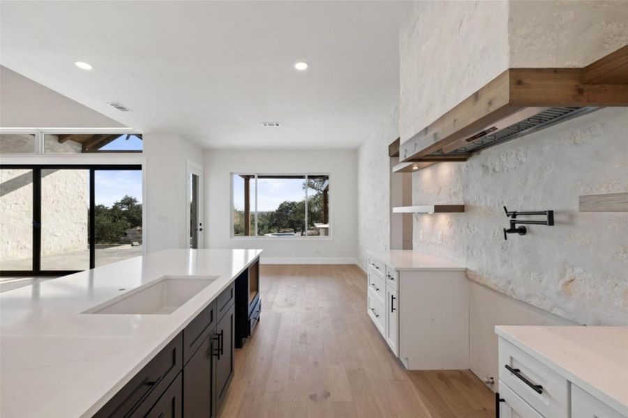 Culinary excellence awaits in this open-concept kitchen featuring an island sink and a stylish range hood. Culinary excellence awaits in this open-concept kitchen featuring an island sink and a stylish range hood.