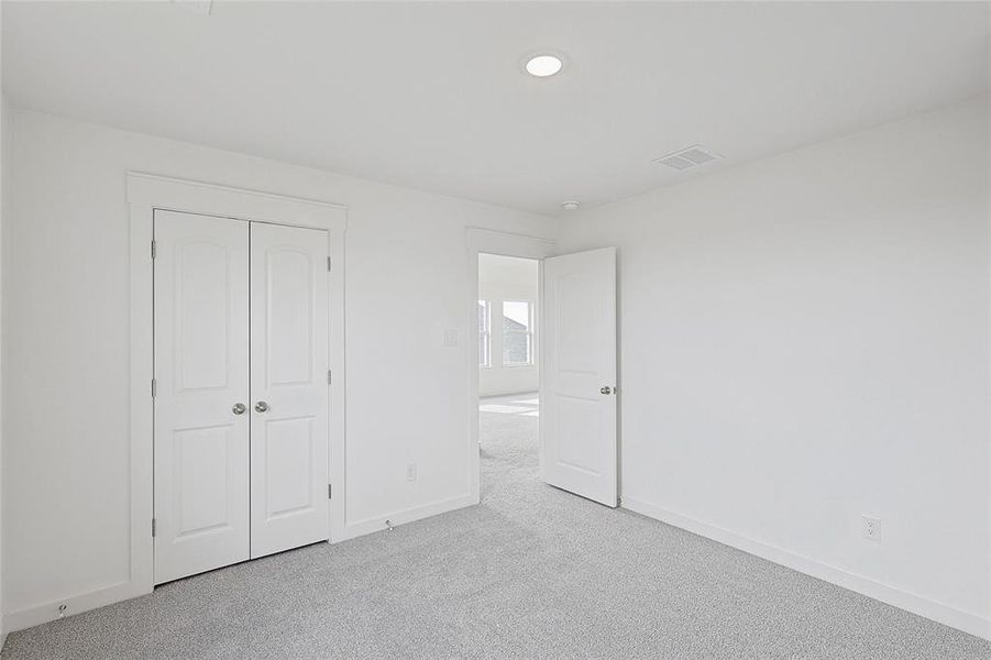 Unfurnished bedroom with light colored carpet and a closet