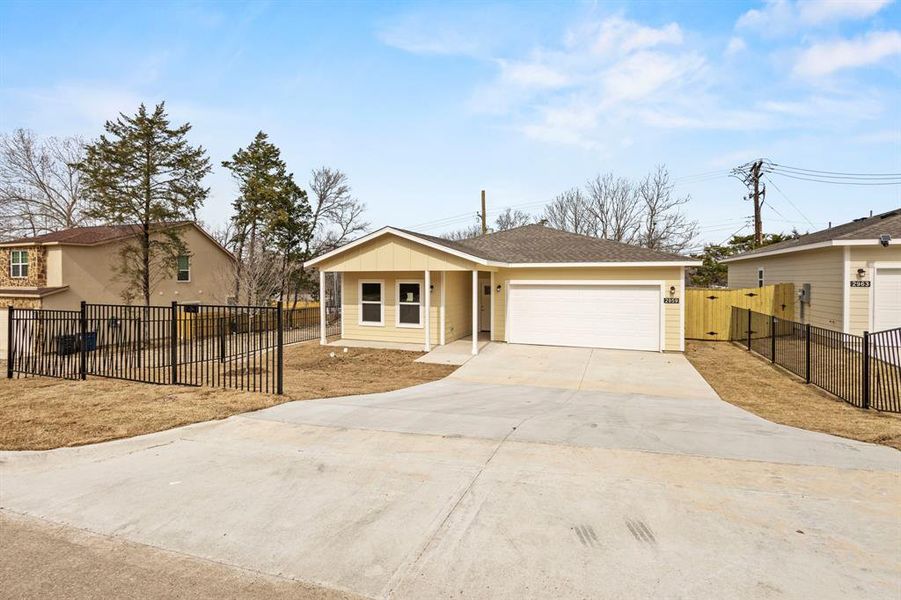 View of front of house with roof with shingles, concrete driveway, board and batten siding, fence, and a garage