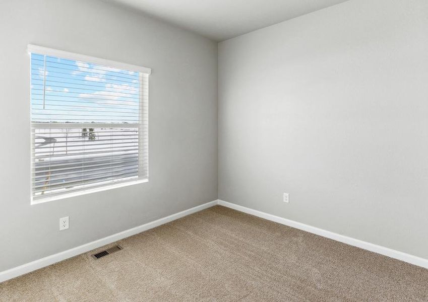 Secondary bedroom with a window and tan carpet.