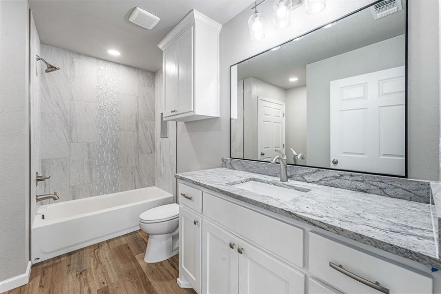 Full bathroom with wood finished floors, toilet, vanity, bathtub / shower combination, and recessed lighting Full bathroom with wood finished floors, toilet, vanity, bathtub / shower combination, and recessed lighting
