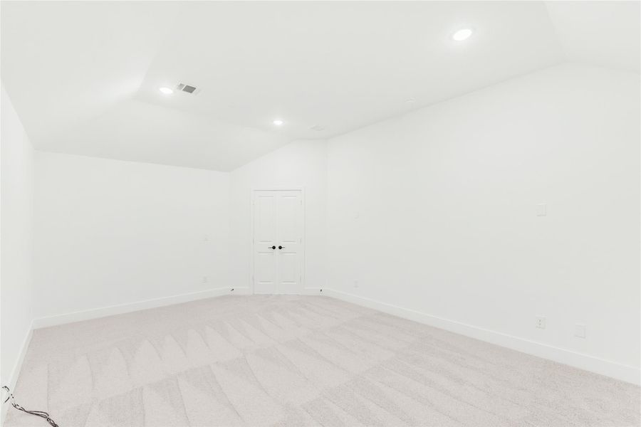 Empty room with vaulted ceiling, recessed lighting, light carpet, and white walls