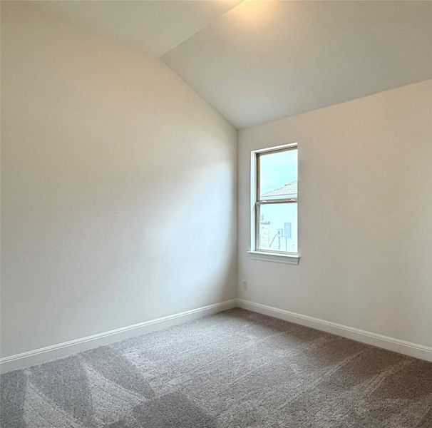 Spare room with vaulted ceiling, dark carpet, and baseboards Spare room with vaulted ceiling, dark carpet, and baseboards