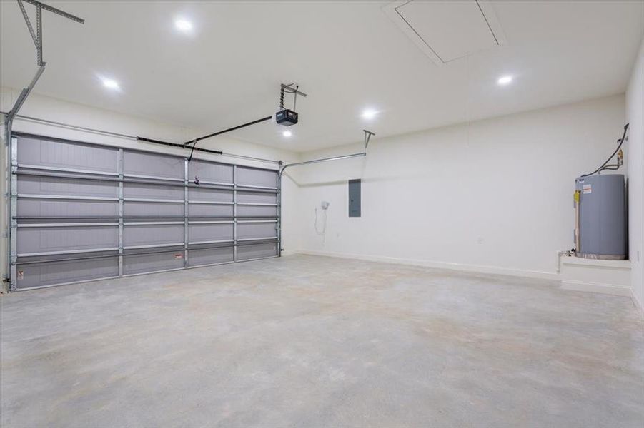 Garage with water heater, electric panel, a garage door opener, and recessed lighting Garage with water heater, electric panel, a garage door opener, and recessed lighting