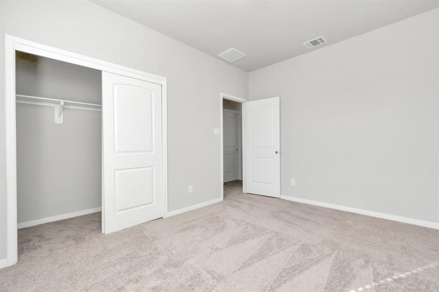 Another view of the secondary bedroom, showcasing its generous size and well-designed layout. The room offers a large closet, neutral carpeting, and soft lighting, making it an ideal space for rest or work. The clean lines and simple design allow for easy customization, ensuring that this room can meet a variety of needs, whether as a guest room, child's bedroom, or home office. **This image is from another Saratoga Home with similar floor plan and finishes, not the June floorplan.**