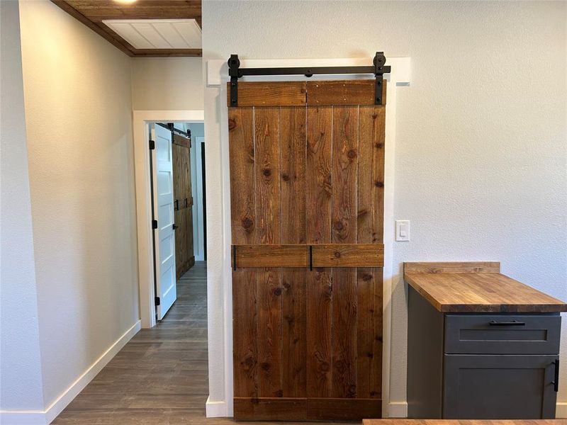 Hall with a barn door, dark wood-style flooring, and a textured wall Hall with a barn door, dark wood-style flooring, and a textured wall