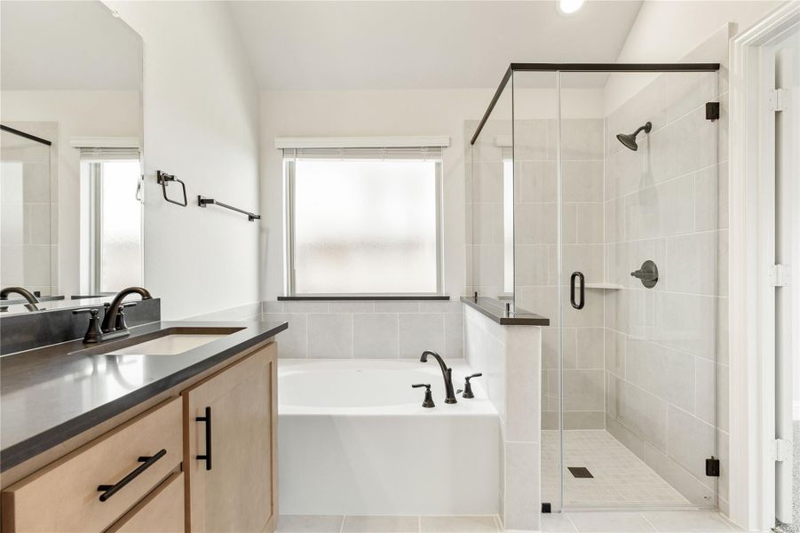 Master bathroom with double vanity, soaking tub, and glass-enclosed tile shower with black fixtures Master bathroom with double vanity, soaking tub, and glass-enclosed tile shower with black fixtures