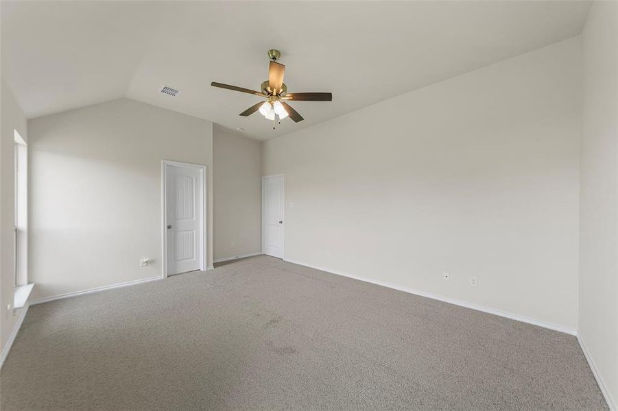 Carpeted empty room with lofted ceiling, a ceiling fan, and baseboards Carpeted empty room with lofted ceiling, a ceiling fan, and baseboards