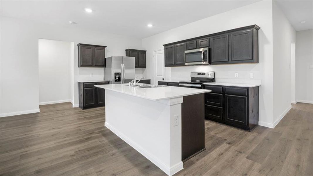 Kitchen with stainless steel appliances, a center island with sink, dark wood finished floors, recessed lighting, and light stone countertops