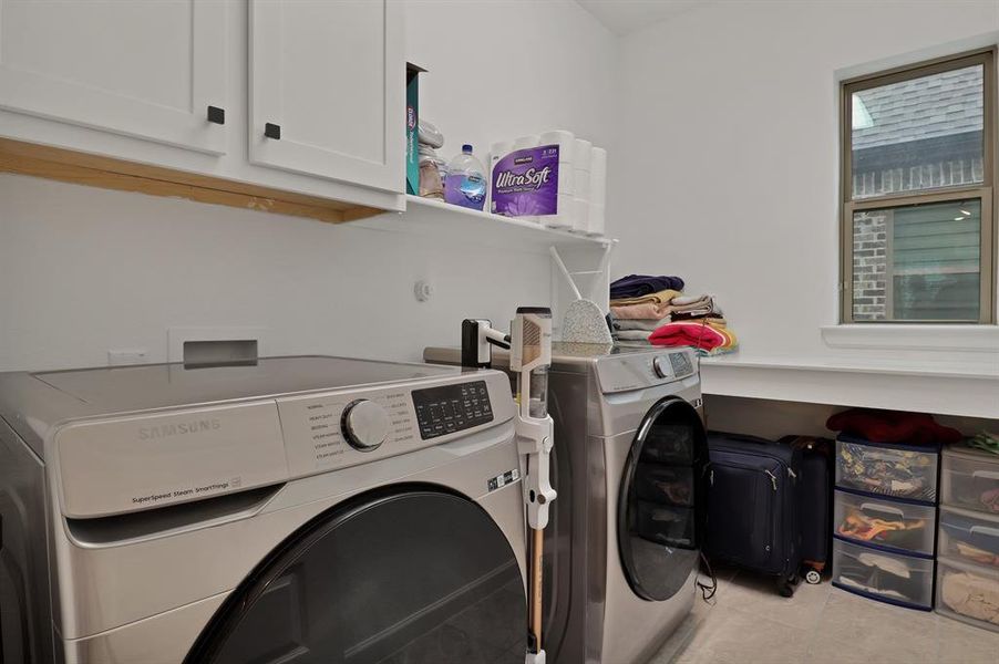 Washer and dryer area with cabinets and folding area