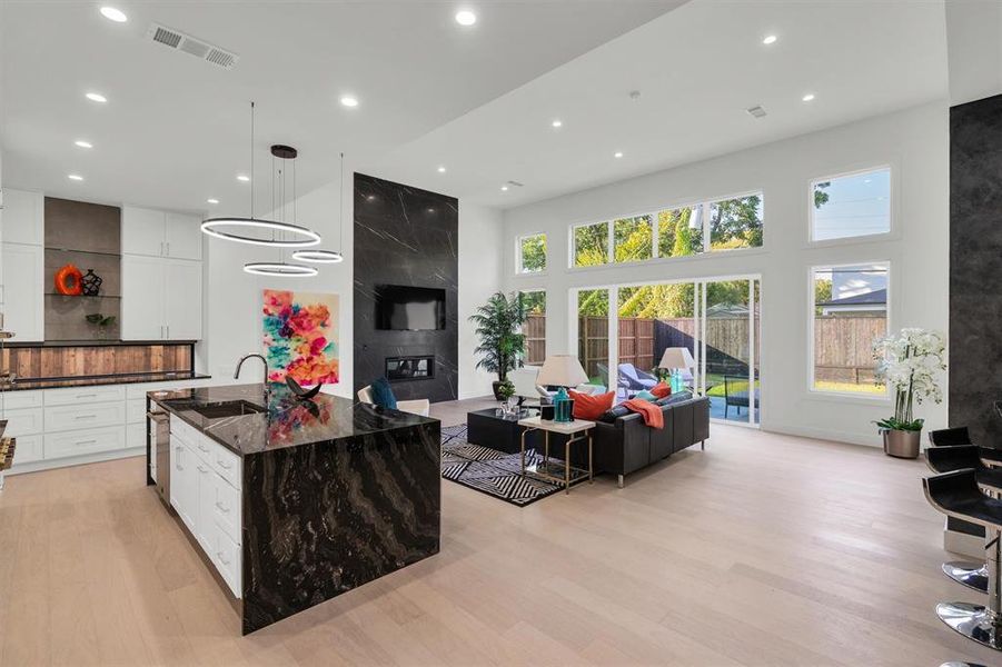 Living area featuring recessed lighting, visible vents, a high ceiling, and light wood-style flooring