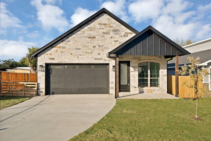 View of front of property with stone siding, concrete driveway, board and batten siding, and a garage