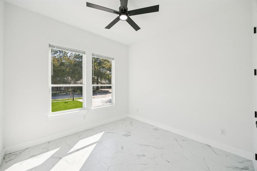 Unfurnished room featuring marble look tile flooring and ceiling fan