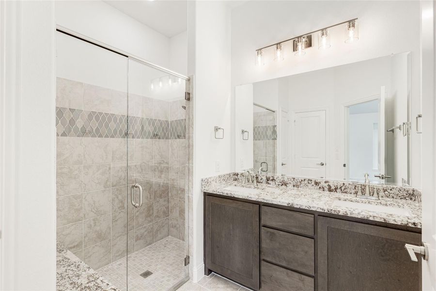 Bathroom with glass walk-in shower, dark wood double vanity, and granite countertops Bathroom with glass walk-in shower, dark wood double vanity, and granite countertops