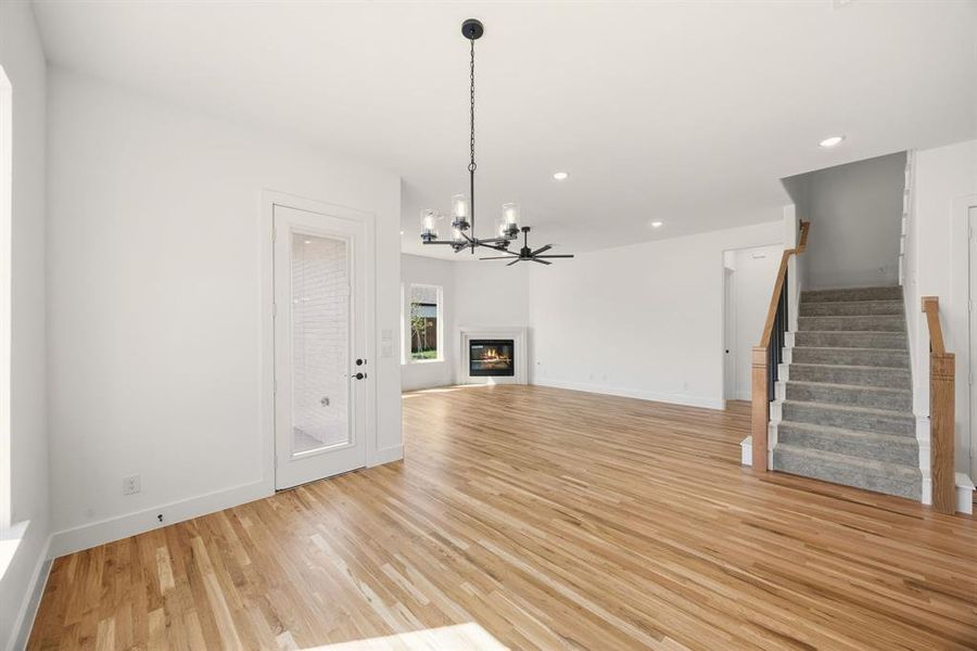 Unfurnished living room featuring a glass covered fireplace, light wood-style flooring, and hanging lights