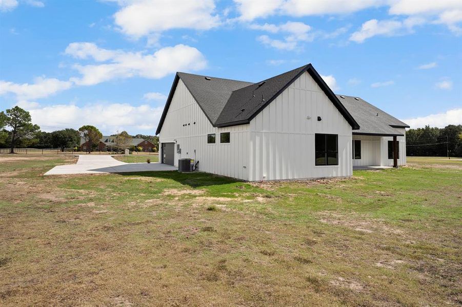 View of home's exterior with a patio area, a yard, and a shingled roof