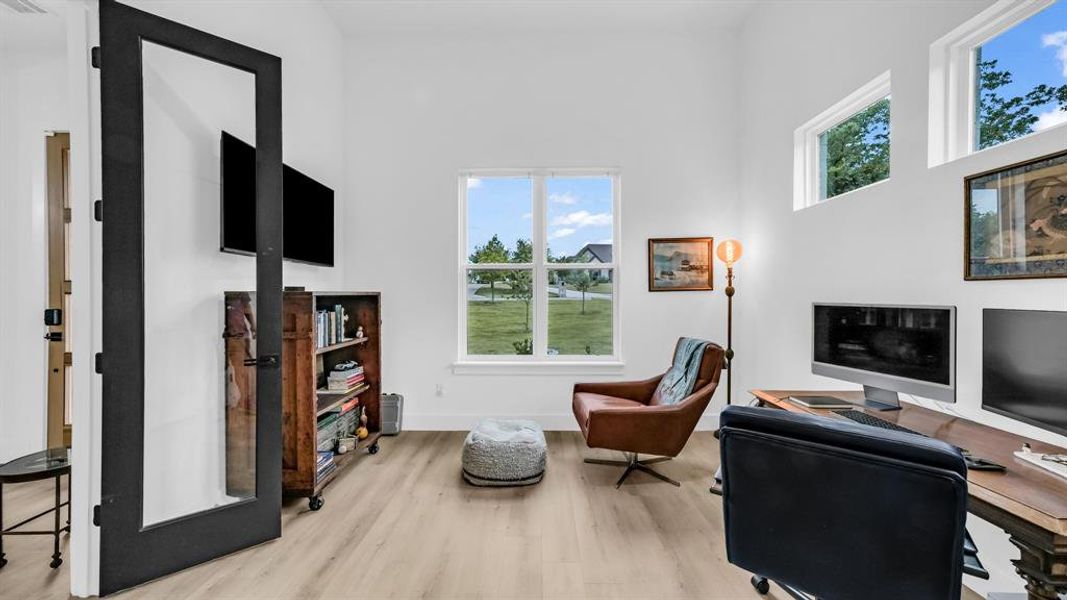 Office space featuring wood finished floors, a high ceiling, and baseboards Office space featuring wood finished floors, a high ceiling, and baseboards