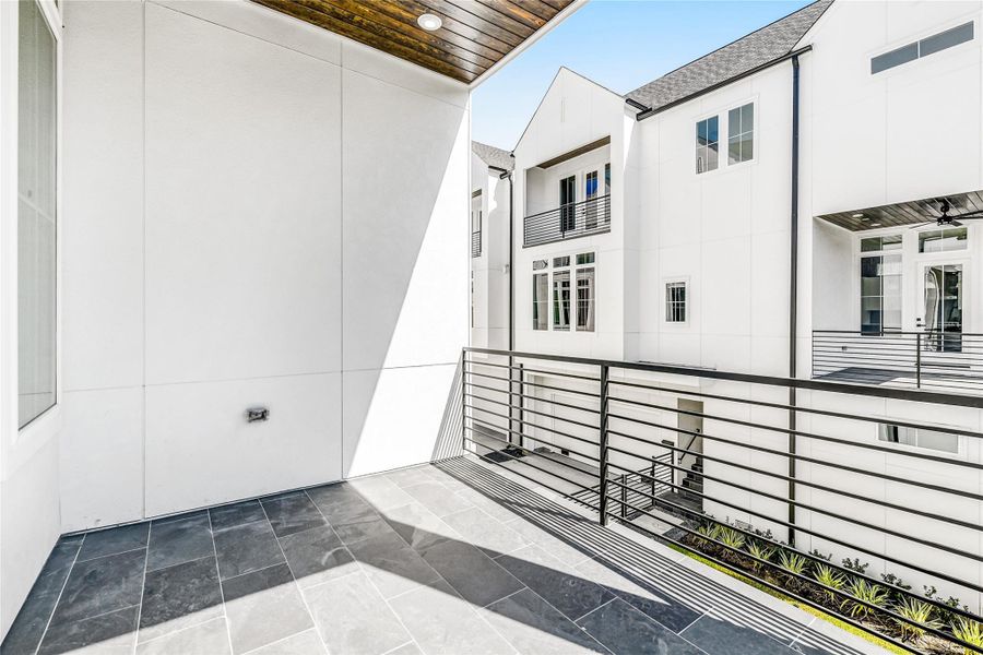 Step directly from the kitchen onto your private covered balcony, perfect for morning coffee or late-night relaxation. With slate flooring, recessed lighting, and metal railing detail, this extension of your living space adds a refreshing outdoor connection—ideal for Houston professionals seeking serenity between work and home life.