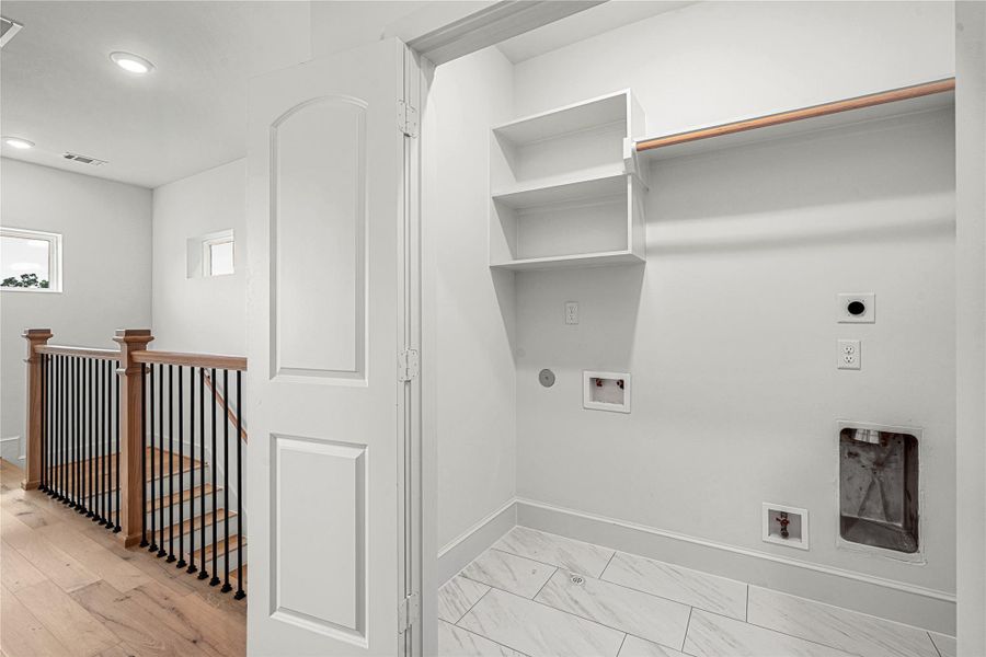 Utility room with hookups for a washer and dryer, tiled flooring, and built-in shelving for convenient storage and organization.