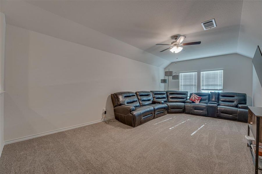 Living room with carpet floors, vaulted ceiling, and ceiling fan