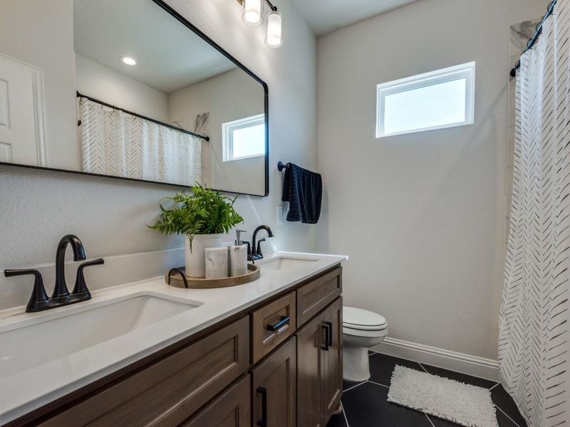 Bathroom featuring vanity, toilet, a healthy amount of sunlight, and tile patterned floors