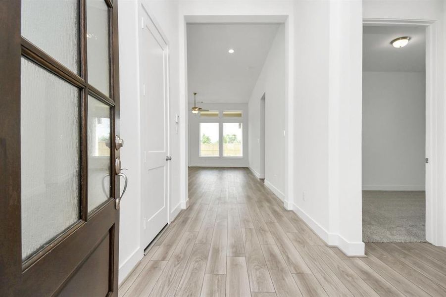 This is a bright, spacious entryway with modern wood-look flooring, leading into an open-concept living area with abundant natural light. The neutral color palette offers a versatile backdrop for a variety of decor styles.