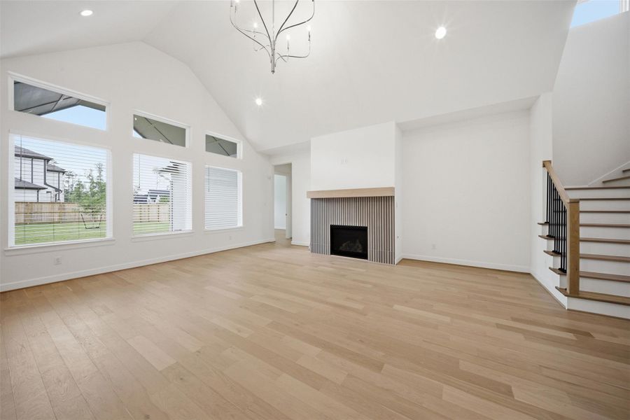 Light-filled living room with soaring ceilings, oversized windows, designer fireplace detail, and an inviting open-concept layout.