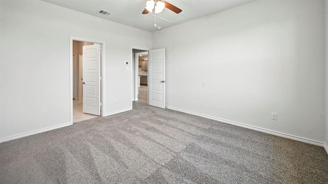 Unfurnished bedroom featuring carpet, attic access, and ceiling fan