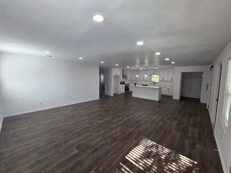 Unfurnished living room featuring dark wood finished floors, recessed lighting, and a textured ceiling Unfurnished living room featuring dark wood finished floors, recessed lighting, and a textured ceiling