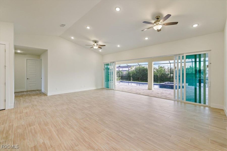 Unfurnished room with wood tiled floors, a ceiling fan, recessed lighting, and vaulted ceiling