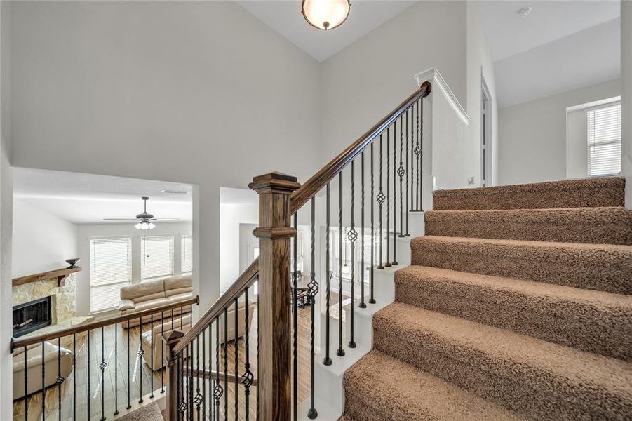 Staircase with a fireplace, hardwood / wood-style floors, and ceiling fan Staircase with a fireplace, hardwood / wood-style floors, and ceiling fan