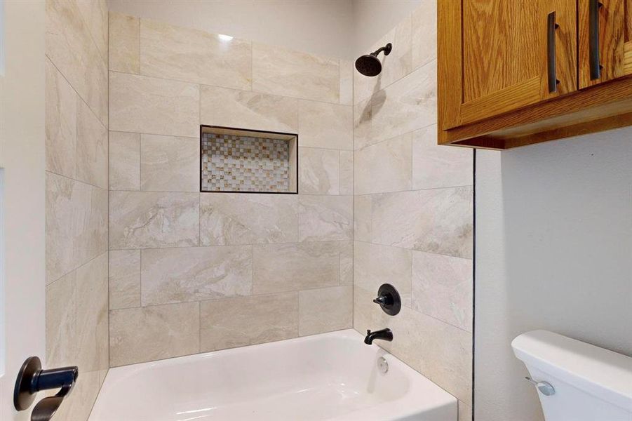 Bathroom with tiled shower / bath combo and toilet