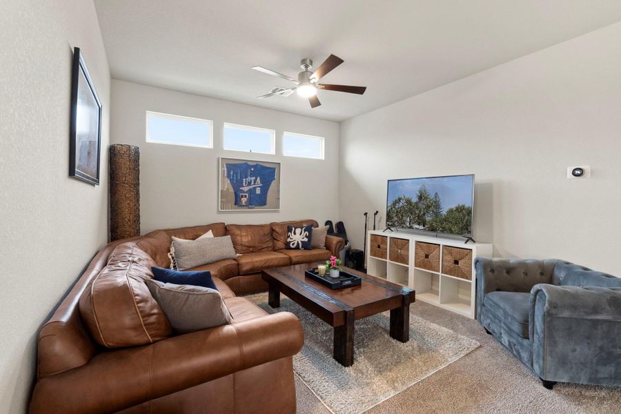 Spacious living area featuring a vaulted ceiling, ceiling fan with light fixture, and high transom windows