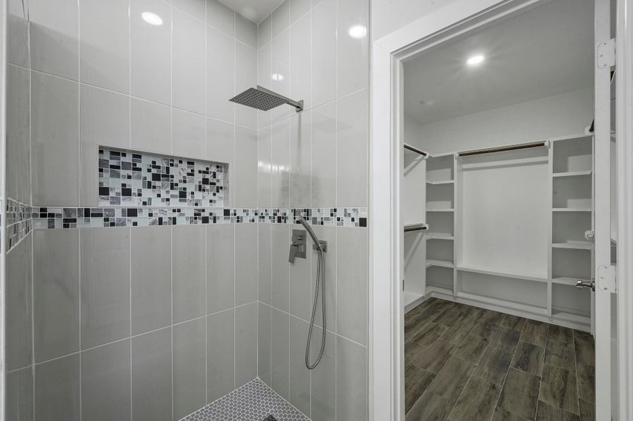 Bathroom featuring a spacious closet, tiled shower, wood finished floors, and recessed lighting