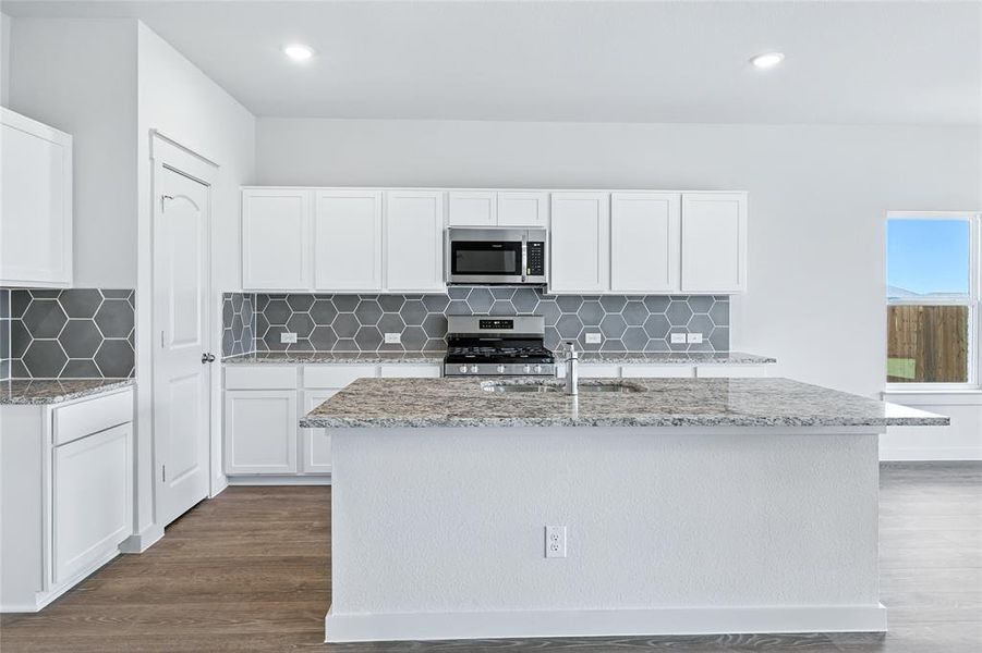Kitchen featuring light stone countertops, white cabinets, decorative backsplash, and recessed lighting Kitchen featuring light stone countertops, white cabinets, decorative backsplash, and recessed lighting