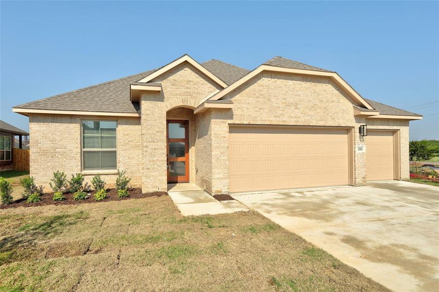 View of front facade featuring roof with shingles, concrete driveway, a garage, brick siding, and a front yard View of front facade featuring roof with shingles, concrete driveway, a garage, brick siding, and a front yard