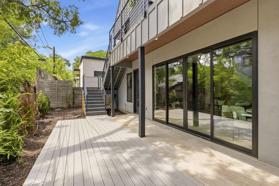 Expansive outdoor deck with composite decking, featuring a multi-panel sliding glass door system providing direct access to the interior