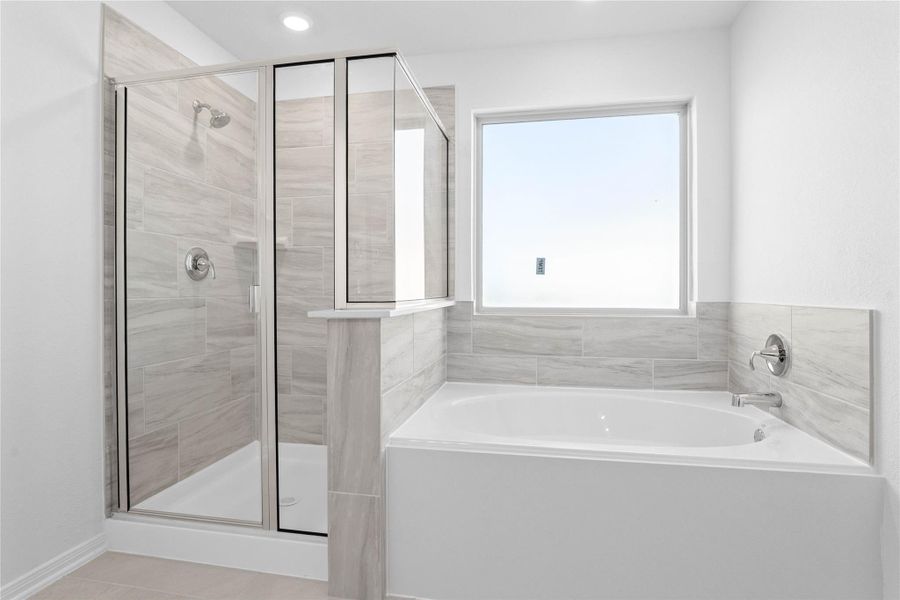This alternate view of the primary bathroom showcases a walk-in shower with a stylish tile surround, a separate garden tub perfect for unwinding after a long day, and a large rain glass window that provides natural light while maintaining privacy.