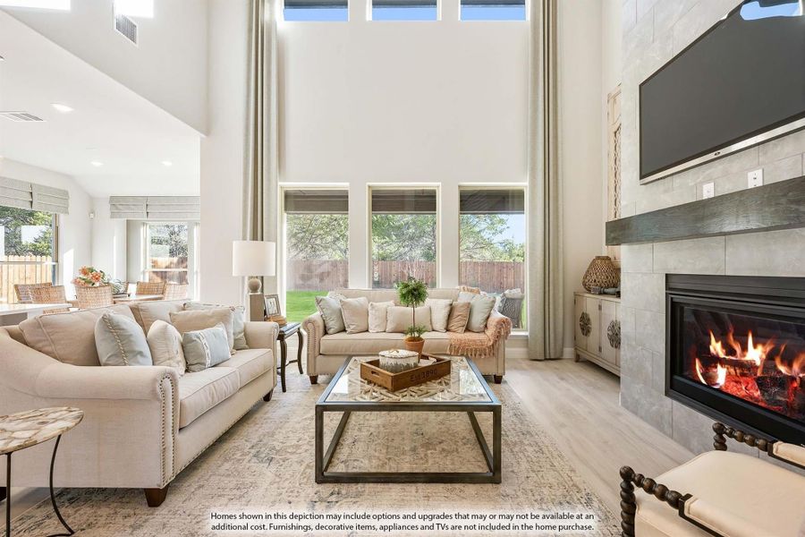Living room with two-story ceiling, tile fireplace, and large windows overlooking backyard