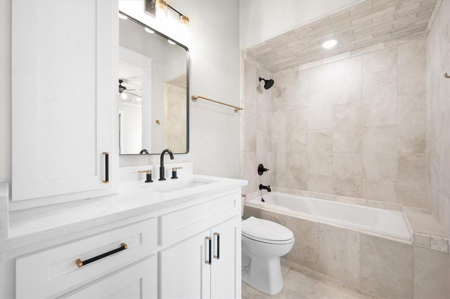 Full bathroom featuring ceiling fan, tiled shower / bath combo, tile patterned flooring, toilet, and vanity