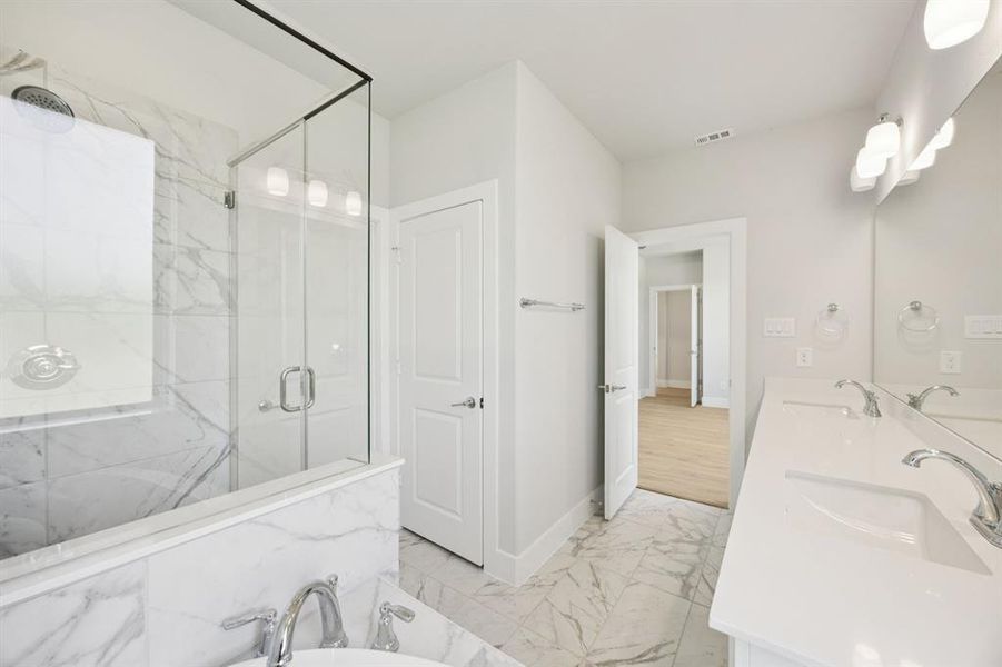 Full bathroom featuring light marble finish flooring, a marble finish shower, double vanity, and a garden tub