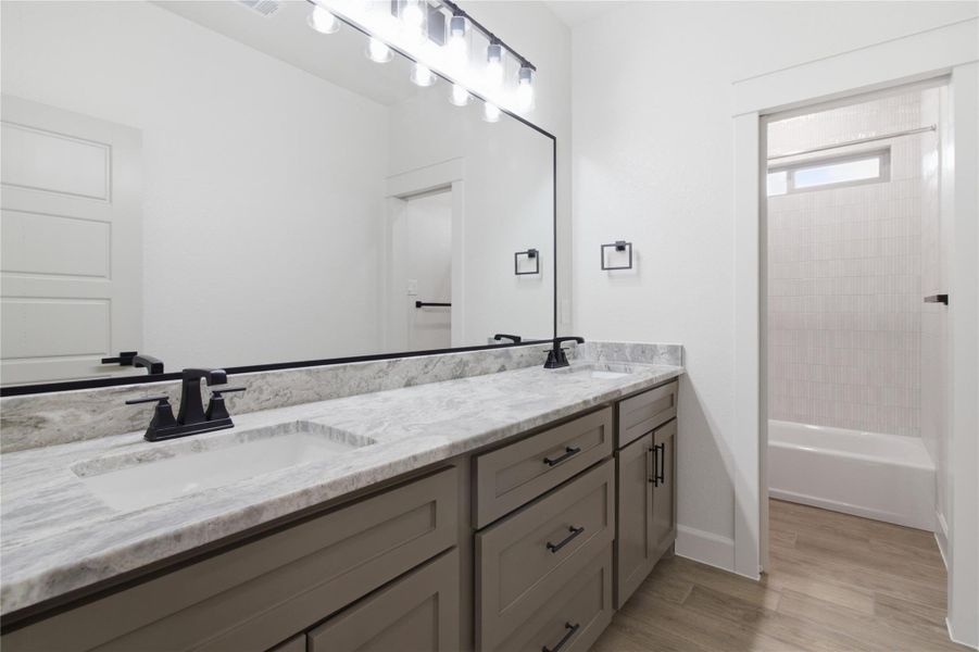 A well-appointed bathroom vanity features dual sinks set in stone counters, reflecting ample light from an overhead fixture. A well-appointed bathroom vanity features dual sinks set in stone counters, reflecting ample light from an overhead fixture.