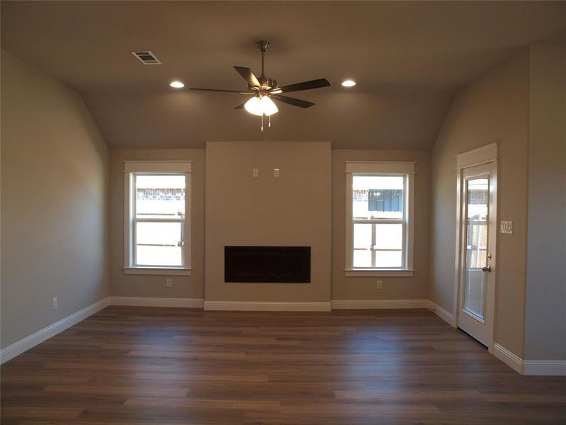 Unfurnished living room featuring lofted ceiling, dark hardwood / wood-style floors, and ceiling fan